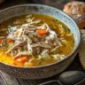 A bowl of Grandma’s Chicken Soup served with crusty bread for a comforting meal.