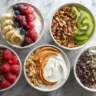 Five colorful high protein yogurt bowls with a variety of fresh toppings